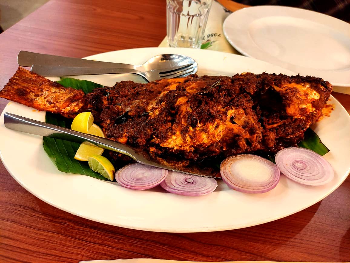 Whole grilled fish on a banana leaf with sliced onion